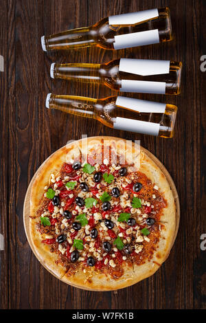 Flasche Bier und Pizza auf einer hölzernen Hintergrund. Vertikale Komposition. Ansicht von oben Stockfoto