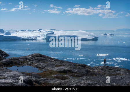 Klimawandel in Grönland. Tourist, der sich schmelzende Eisberge ansieht. Stockfoto