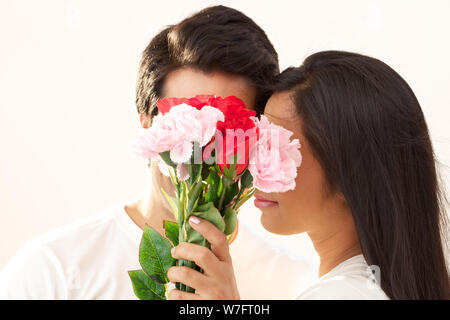 Paar romancing hinter einen Blumenstrauß Stockfoto