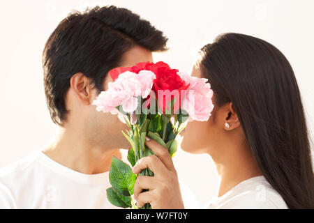 Paar romancing hinter einen Blumenstrauß Stockfoto