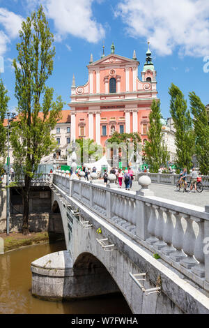 Die Rosa Franziskanerkirche in Prešerenplatz und Touristen zu Fuß über die drei Brücken über den Fluss Ljubljanica ljubljana Slowenien EU Europa Stockfoto