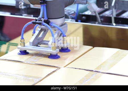 Der Roboterarm transfers Karton zu Fließband; close up Stockfoto
