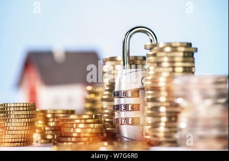 Codeschloss mit mehrere Stapel Münzen und Haus im Hintergrund | Verwendung weltweit Stockfoto