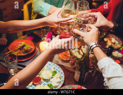 Menschliche Hände mit Gläser Rotwein zu klirren über serviert. Stockfoto