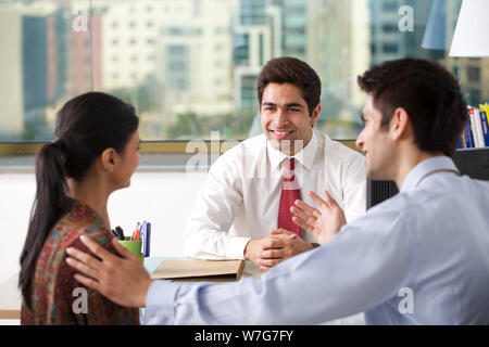 Junges Paar, das mit Finanzberater in einem Büro diskutiert Stockfoto
