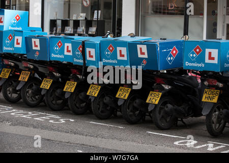 Domino's Pizza Delivery Roller untätig außerhalb einer Niederlassung auf Foley Street, London, UK Stockfoto