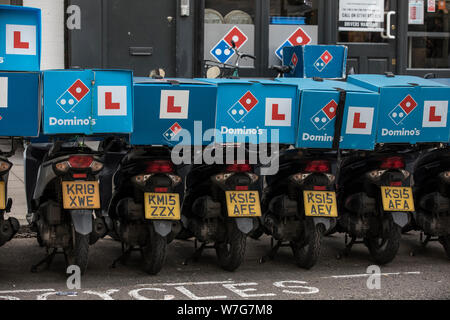 Domino's Pizza Delivery Roller untätig außerhalb einer Niederlassung auf Foley Street, London, UK Stockfoto