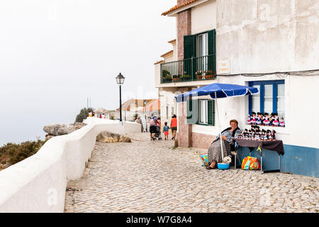 Nazare, Portugal - Juli 19, 2019: Frau verkaufen Puppen in traditioneller Kleidung am Miradouro auf ein DUNSTIGER Tag Stockfoto