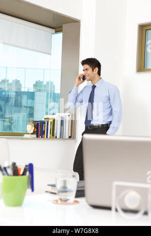 Unternehmer, die auf einem Mobiltelefon in einem Büro im Gespräch Stockfoto