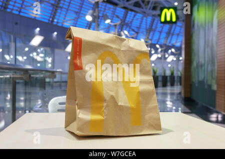 Moskau, Russland - Februar 07, 2019: McDonald's braune Papiertüte mit unscharfen Kiosk in der Shopping Mall. Stockfoto