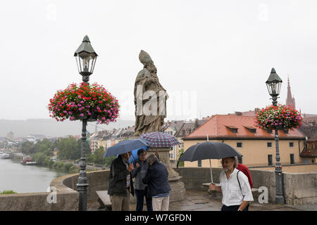 Menschen mit Regenschirm ist Chatten an der Alten Brücke über den Main in Regen Wetter in Würzburg, Deutschland Stockfoto