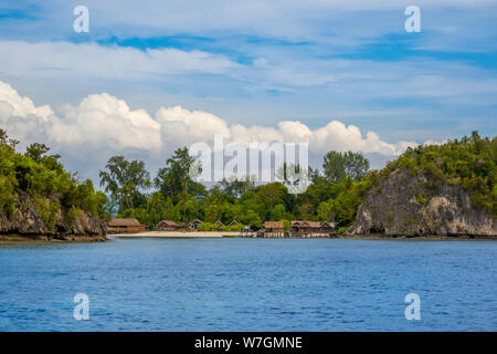 Insel in Indonesien. Raja Ampat. Mehrere traditionelle Hütten am Ufer zwischen den Felsen und der Strand Stockfoto