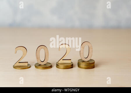 2020 - Holz- Zahlen auf Stapel von Münzen auf einem hellen Hintergrund. Kreative Idee für das Wachstum von Unternehmen, Steuern, Investitionen und Banking, Neues Jahr Stockfoto