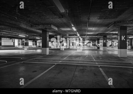 Grunge, schwach beleuchteten leeren Parkhaus mit Beleuchtung und eine Ausfahrt von der Decke hängt. Stockfoto