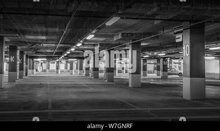 Grunge, schwach beleuchteten leeren Parkhaus mit Beleuchtung und eine Ausfahrt von der Decke hängt. Stockfoto