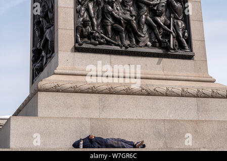 Weiße Kaukasier Männlich in hoodie mit Kapuze über Gesicht und Bier Lagerbier schlafen kann auf dem Sockel Schritte von Nelson's Column auf den Trafalgar Square, London, UK. Stockfoto