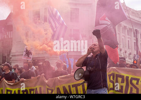 Anti-faschistischen Demonstranten in Opposition zur freien Tommy Robinson Protestkundgebung in London, UK. Banner und Führer mit Megaphon. Farbige flare Rauch Stockfoto