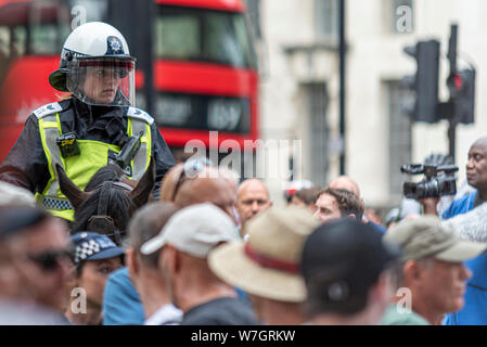 Eine eingefleischene Polizist auf dem Pferderücken, die besorgt auf der Protestkundgebung von Free Tommy Robinson in London, Großbritannien, schaut. Berittene Polizei Reiter Stockfoto