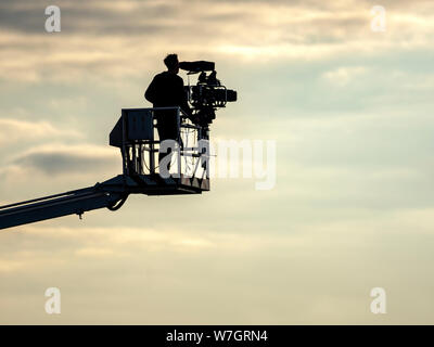 Ein TV-Kameramann steht auf einem Cherry Picker Kran, wie er Filme ein Pferd, das Treffen in Musselburgh Racecourse, East Lothian, Schottland, Großbritannien. Stockfoto