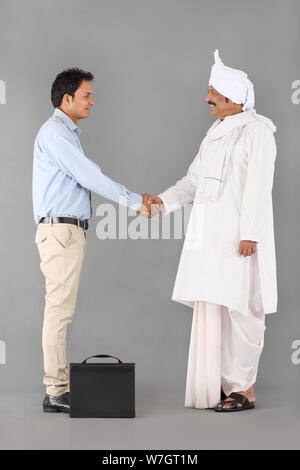 Executive schüttelt die Hände mit einem ländlichen Mann Stockfoto