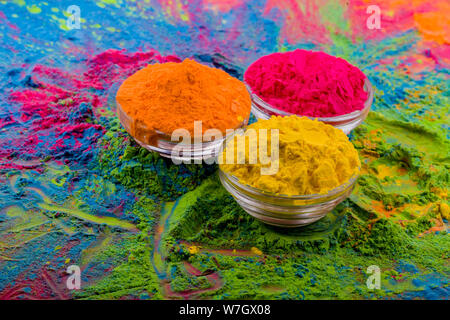 Farbenfrohe Holi-Pulver in Tassen auf weißem rustikalen Holztisch. Draufsicht mit Textfreiraum. Stockfoto