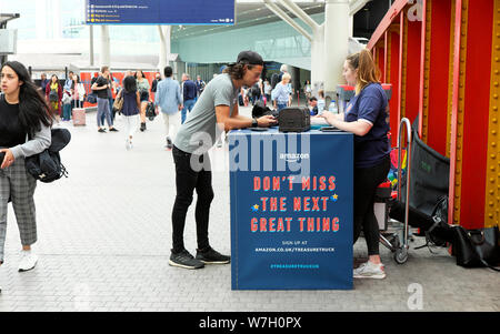 Leute am Amazon Treasure Truck Kiosk mit Werbung auf der Halle an der Paddington Station in West London England Großbritannien Großbritannien KATHY DEWITT Stockfoto