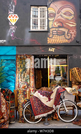 Ein antiker Händler Shop auf dem Flohmarkt in Clignancourt, Paris mit persischen Teppichen und einem Fahrrad außerhalb Stockfoto