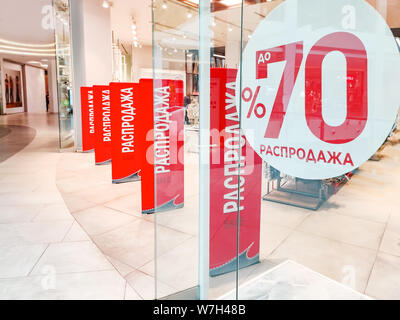 Saisonale Rabatte Verkauf 70 percen im Store. Red Banner mit Text auf Russisch und Englisch sprachen auf einem Windows-shop am Eingang des Stockfoto