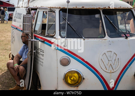 Ein Mann sitzt in der Seitentür eines rostigen Vw Camper van Stockfoto