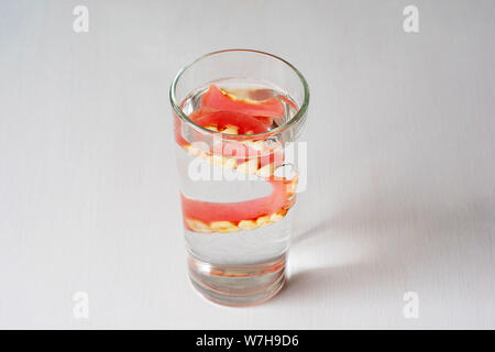 Zahnersatz in ein Glas mit Wasser auf einem weißen Hintergrund. Stockfoto