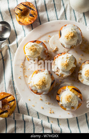 Hausgemachte gegrillte Pfirsiche mit Eis und zerbröckelt Stockfoto