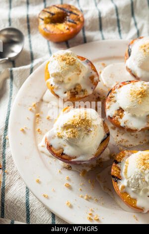 Hausgemachte gegrillte Pfirsiche mit Eis und zerbröckelt Stockfoto