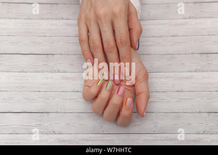 Bunte moderne Maniküre, Nail Design. Sommer Stimmung, auf Holz- Hintergrund. Ansicht von oben Stockfoto