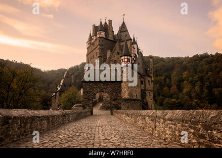 Straße mit Kopfsteinpflaster mit Bogen in Richtung der mittelalterlichen Burg Eltz Burg bei Sonnenaufgang in der Nähe von Mosel in Wierschem, Rheinland-Pfalz, Deutschland. Stockfoto