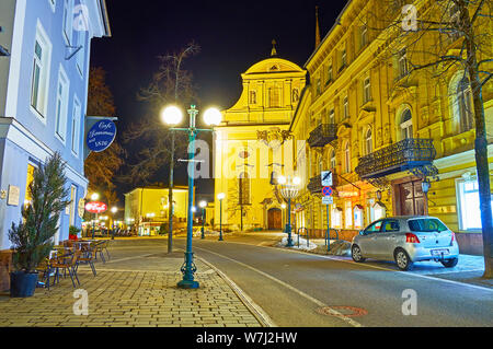 BAD ISCHL, Österreich - Februar 20, 2019: Abend Franz Joseph Strasse mit Blick auf die beleuchtete St. Nikolaus Pfarrkirche und klassischen Gebäuden, auf Stockfoto