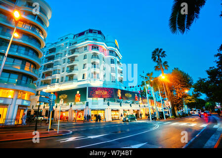 Stadtbild von Hauptstraße und der Straße mit luxuriösen Hotels und Geschäften in der Nacht. Cannes, Frankreich, Côte d'Azur Stockfoto