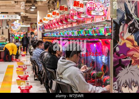 Die Spieler sitzen an Spielautomaten im Casino, Tokio, Japan Stockfoto