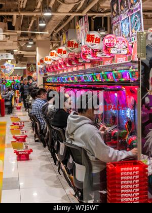 Die Spieler sitzen an Spielautomaten im Casino, Tokio, Japan Stockfoto