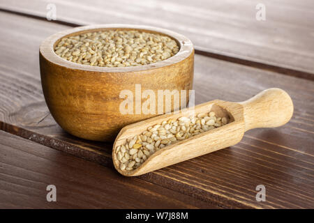 Menge ganze ungeschälte Sesamsamen in Houten mit Holz- Schaufel auf braunem Holz Stockfoto
