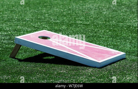 Eine rot-weiße hausgemachte Holz- cornhole Board ist auf einem grünen Rasenfeld. Stockfoto