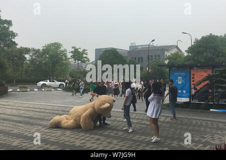 Ein chinesischer Mann der 'Reichen' der zweiten Generation zahlt Hof zu einem Mädchen wie hält er eine 2,5 Meter hohe Riesen Puppe Bär am Hangzhou Normal University in Hangzhou Stockfoto