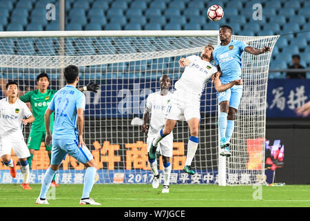Kamerunischer Fußballspieler Benjamin Moukandjo, rechts, der Jiangsu Suning, leitet die Kugel gegen kroatischen Fußballspieler Nikica Jelavic von Guizhou Er Stockfoto