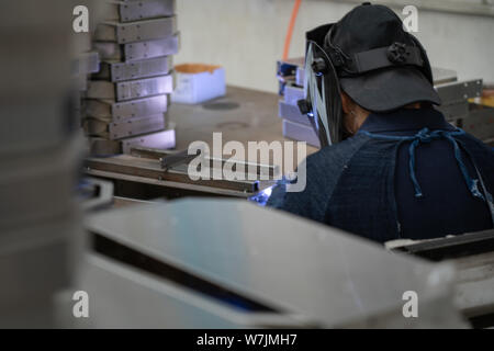 Chinesischer Mann Schweißen von metallischen Bauteilen in einer Fabrik in der Nähe von Shanghai, China. Stockfoto