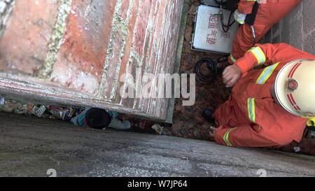 Chinesische Feuerwehrleute versuchen, den neun Jahre alten chinesischen Jungen zu retten, mit dem Beinamen Huang immer stecken in einem Raum so schmal wie 20 Zentimeter zwischen Wänden in Stockfoto