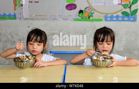Chinesische twin Mädchen Liu Yuting, rechts, und Liu Yuyao kostenloses Mittagessen in der Grundschule Nr. 4 in Jianhe County, qiandongnan Miao und Dong Autonomen nehmen Stockfoto