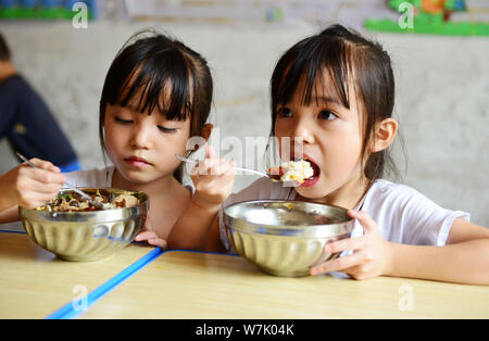 Chinesische twin Mädchen Liu Yuting, rechts, und Liu Yuyao kostenloses Mittagessen in der Grundschule Nr. 4 in Jianhe County, qiandongnan Miao und Dong Autonomen nehmen Stockfoto