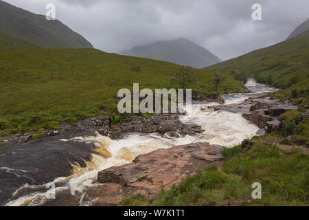 Der Fluss fließt durch Glen Etive Etive in den schottischen Highlands in der Nähe von Glencoe auf einem Moody regnerischen Tag mit niedrigen Cloud Stockfoto