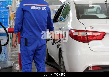 ---- Ein chinesischer Arbeiter tankt ein Auto an einer Tankstelle von SINOPEC in Nanjing, Provinz Jiangsu, China, 25. Mai 2017. China ist in Fra Stockfoto