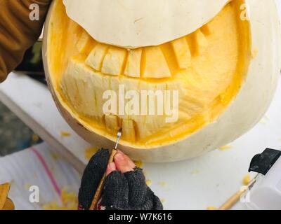 Schnitzen Kürbis Kunst in Aktion hand mit Werkzeug Kürbis lächeln Halloween Dekoration tradition Stockfoto