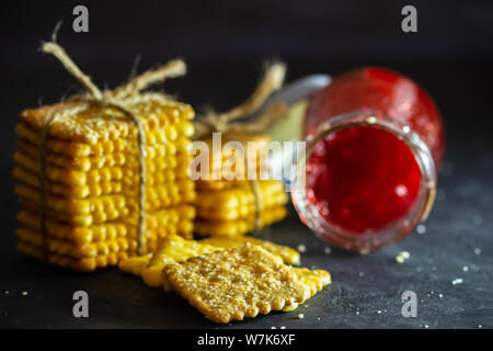 Cracker mit Hanf und Erdbeermarmelade Flasche auf dem Tisch im dunklen Hintergrund gebunden. Stockfoto